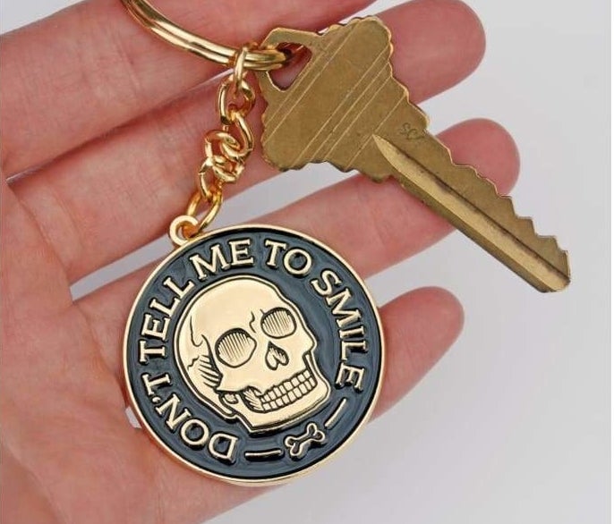A keychain with a skull that says &quot;don&#x27;t tell me to smile&quot;