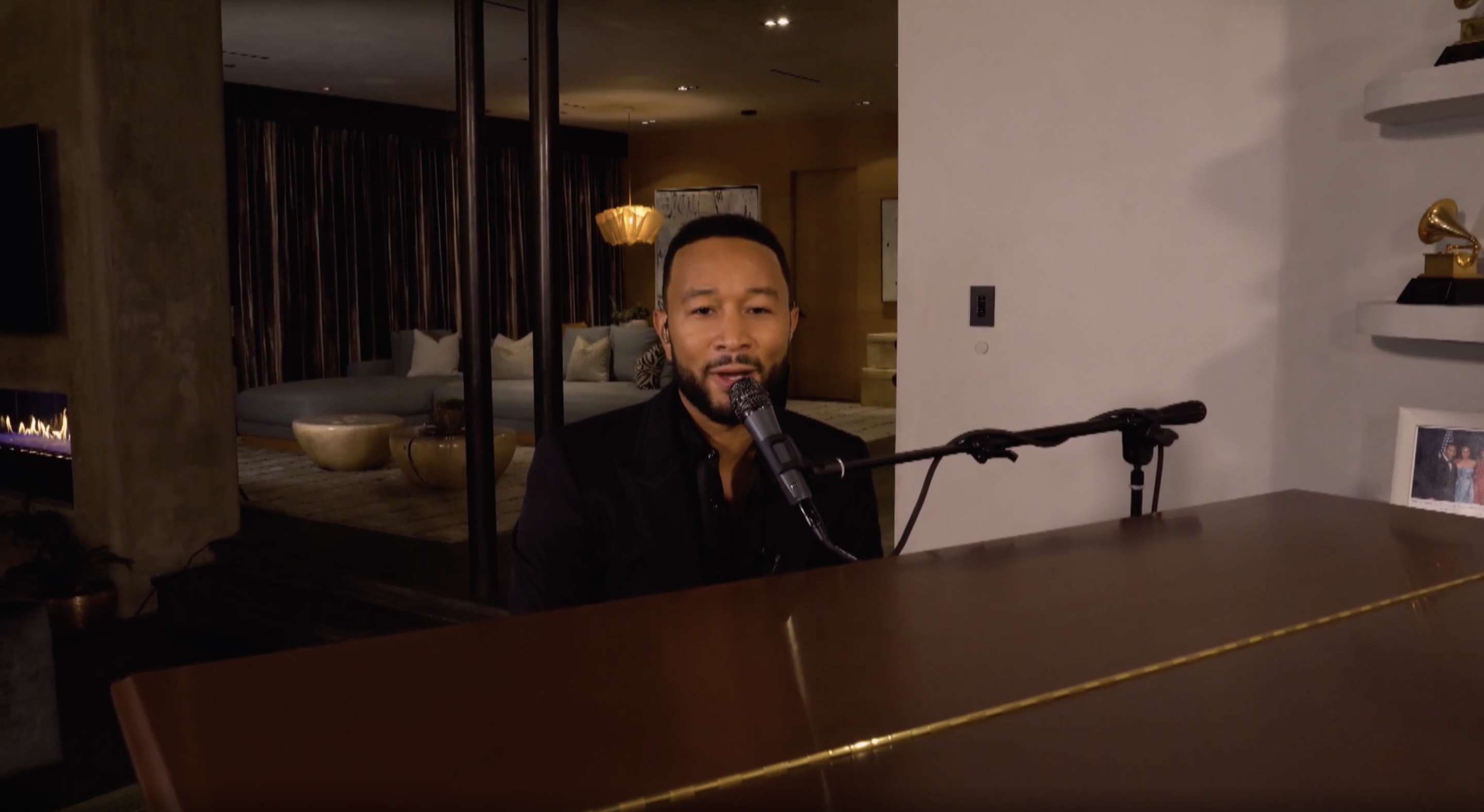 John Legend sitting at a grand piano