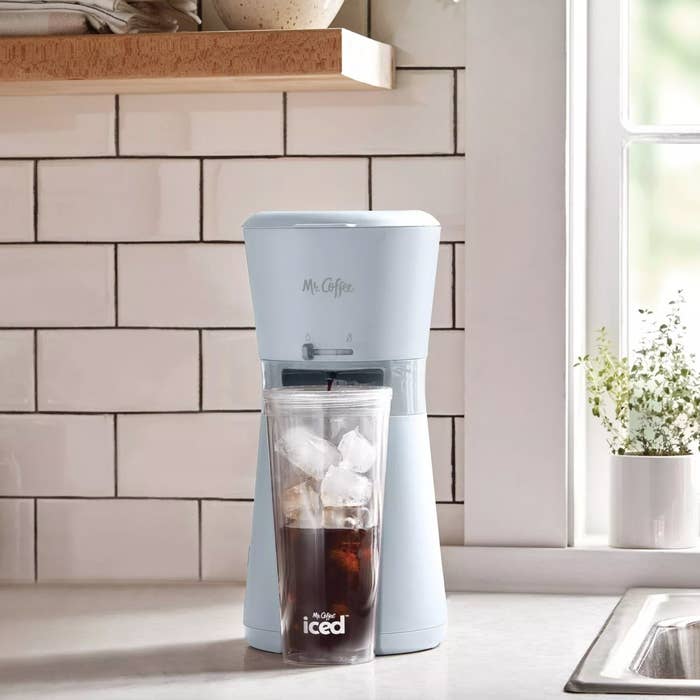 A blue coffee maker pouring over ice
