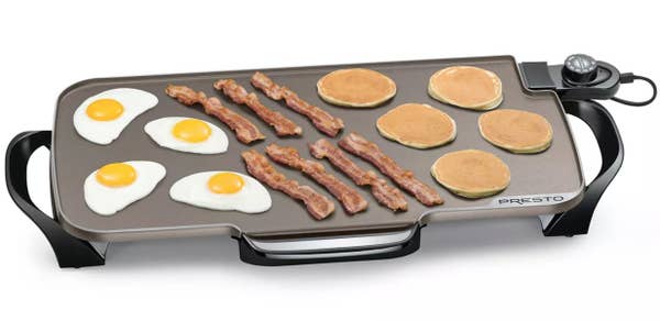 An electric griddle cooking eggs, bacon, and pancakes