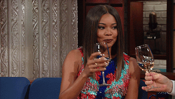 Gabrielle Union drinking white wine and laughing.