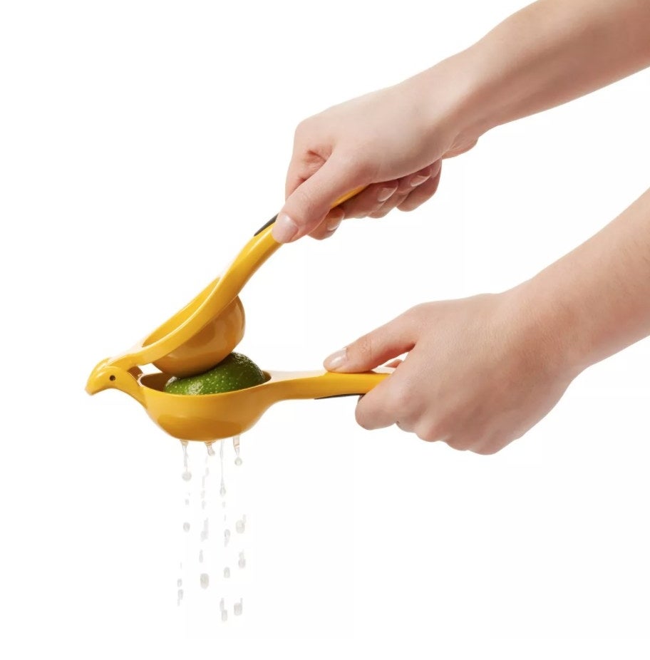 A yellow citrus juicer squeezing a lime