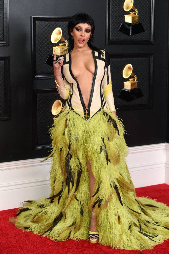 Doja Cat walks the red carpet at the 2021 Grammys in a fitted motorcycle jacket dress with a feathered bottom
