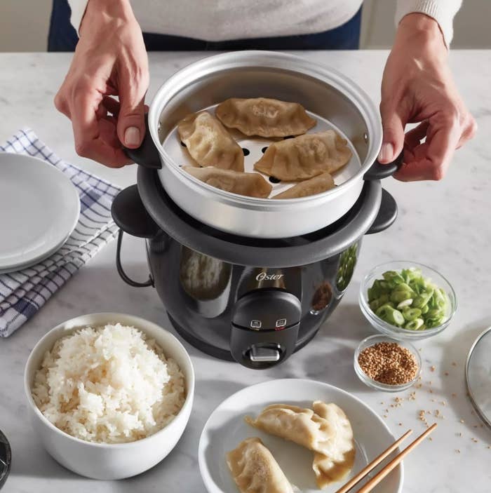 A rice cooker with tray for steaming food, showing dumplings as an example