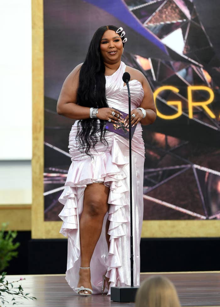 Lizzo showing of some leg in a ruffled gown and bedazzled clips in her hair