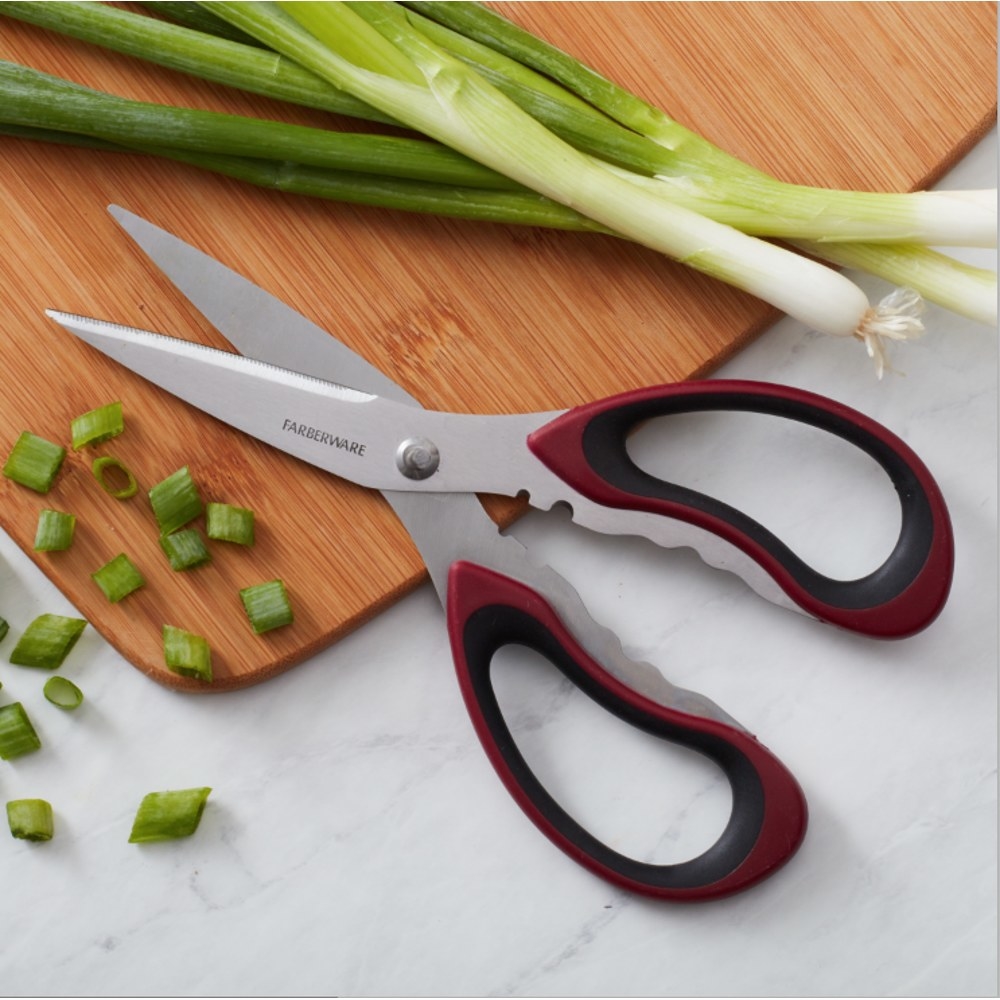 a pair of kitchen sheers cutting green onion