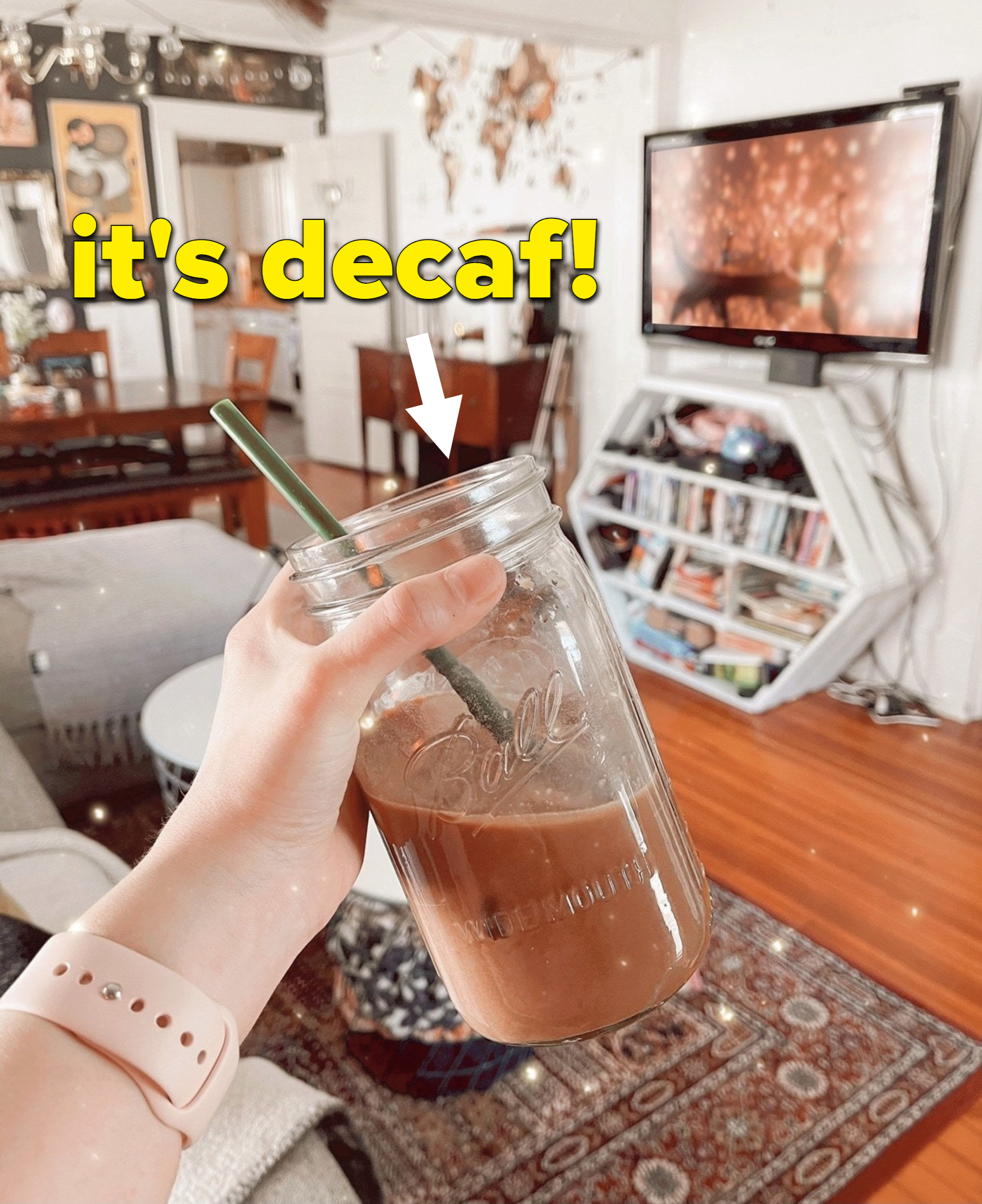 A person holding a jar of iced coffee