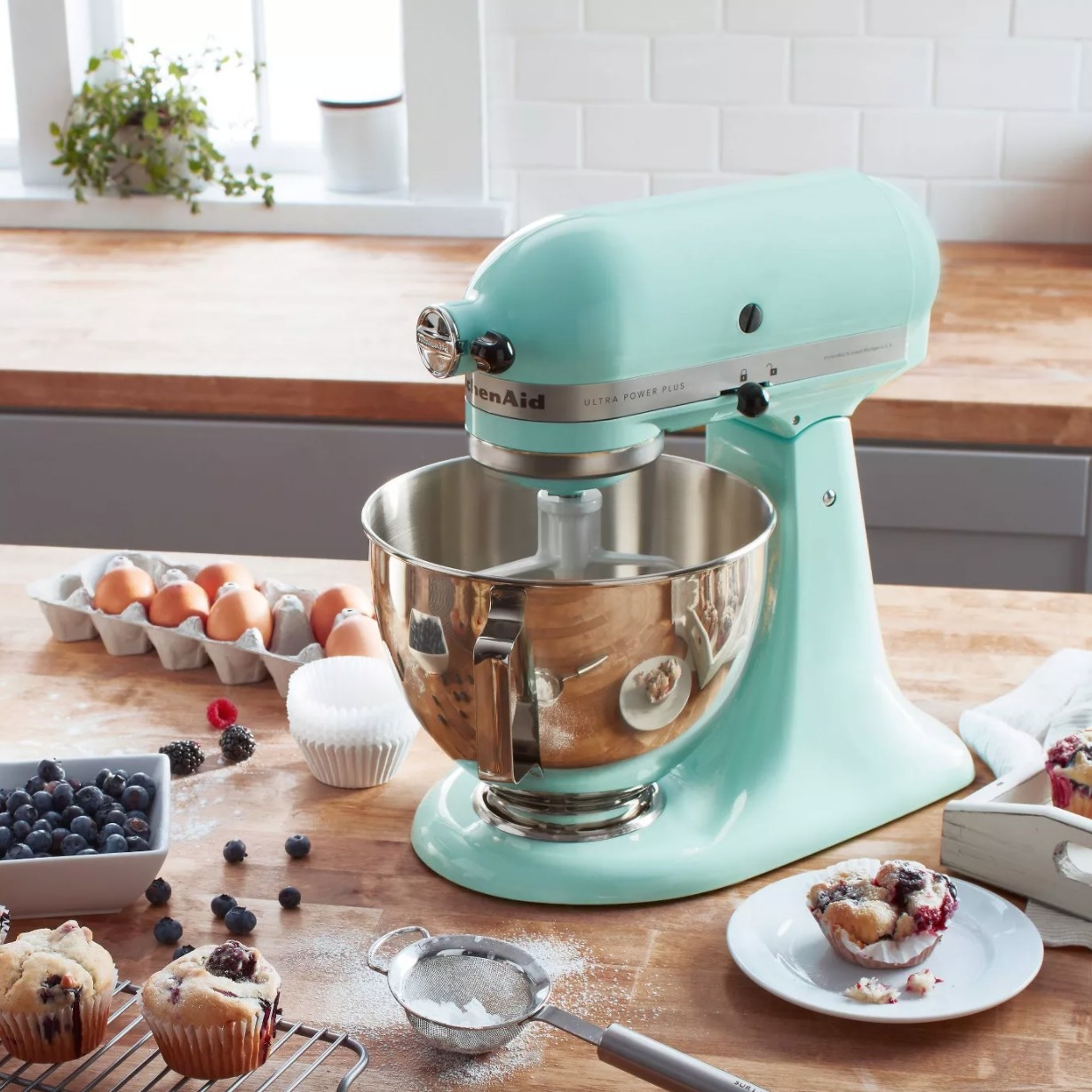 A teal blue stand mixer with paddle attachment and silver mixing bowl