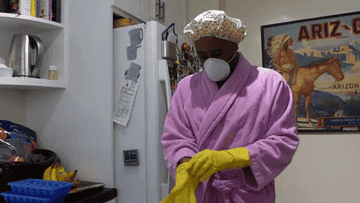 Person in a bath robe and a shower cap puts on yellow rubber gloves