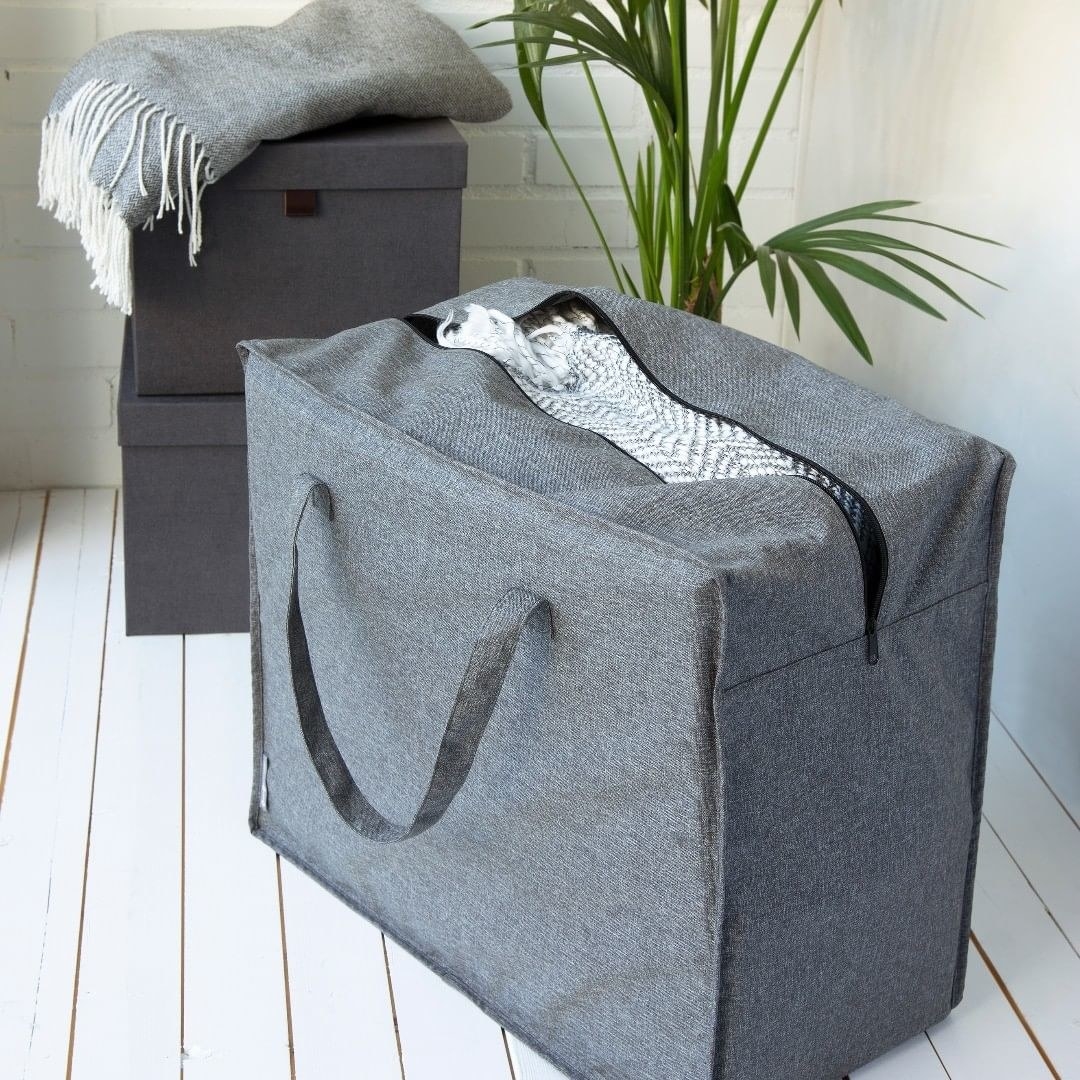 A large cube-shaped fabric bag, unzipped to show off the linens inside