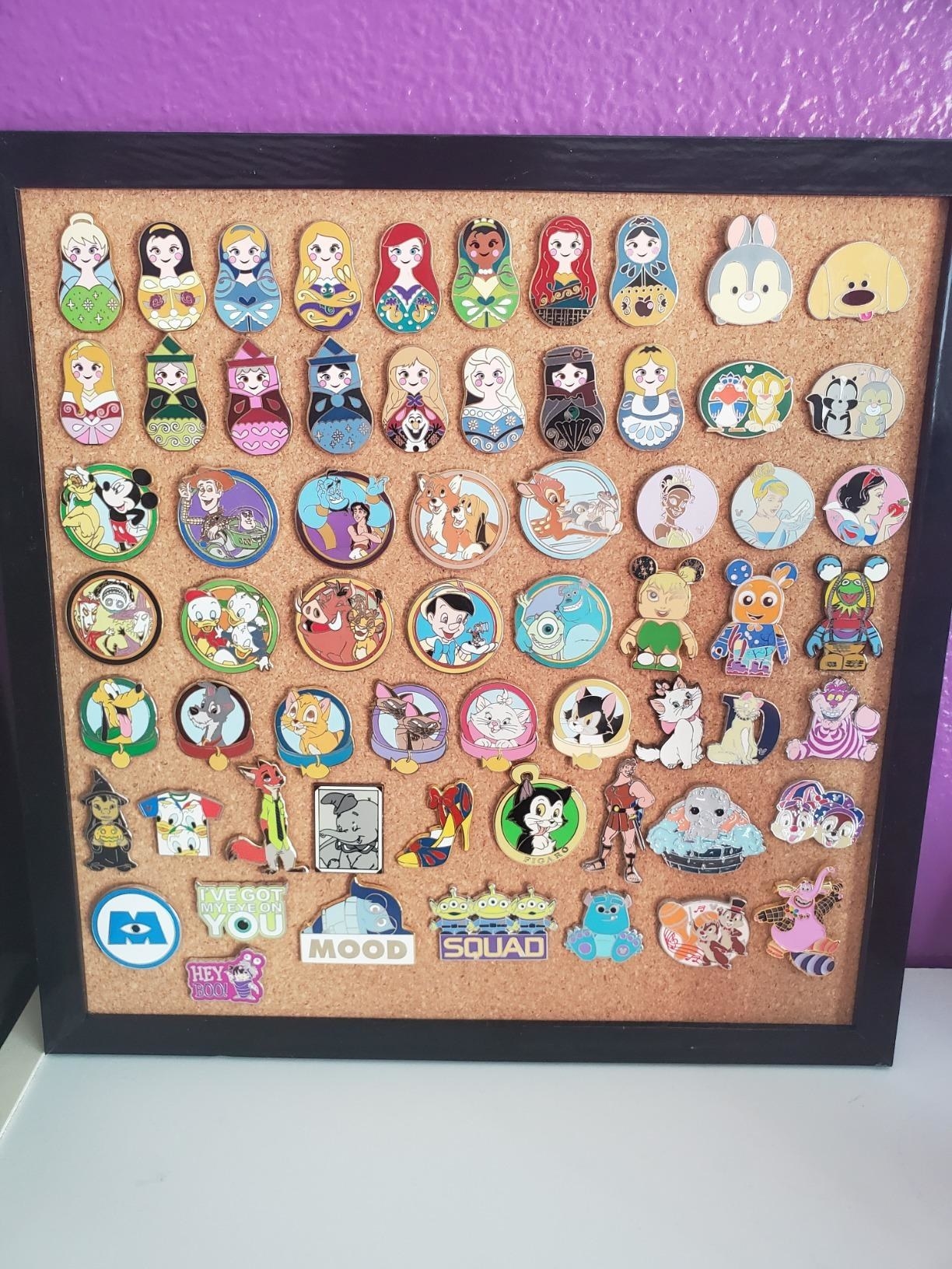 reviewer image of one HB life cork board with dozens of disney inspired enamel pins