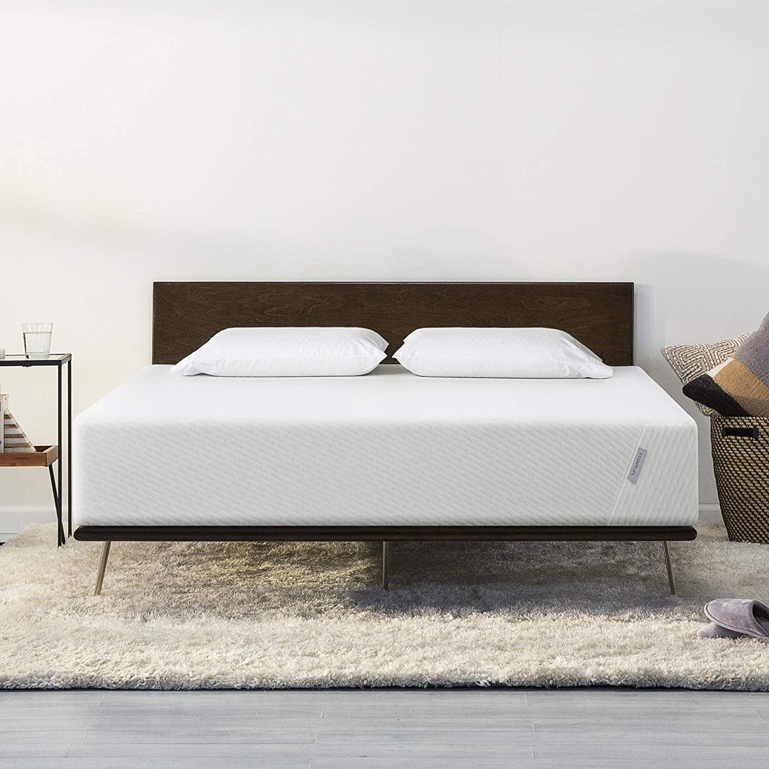 A white mattress on a bed frame 