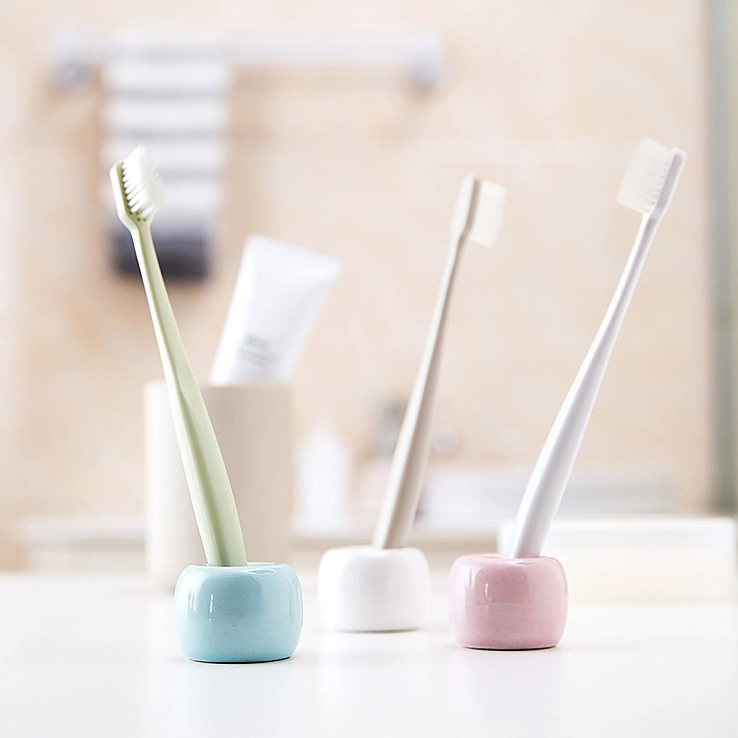 Three ceramic and cylindrical holders with a toothbrush in each 