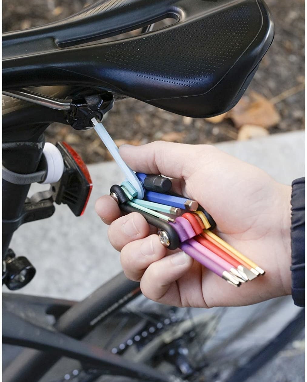 A person using the multi-purpose tool on their bike seat 