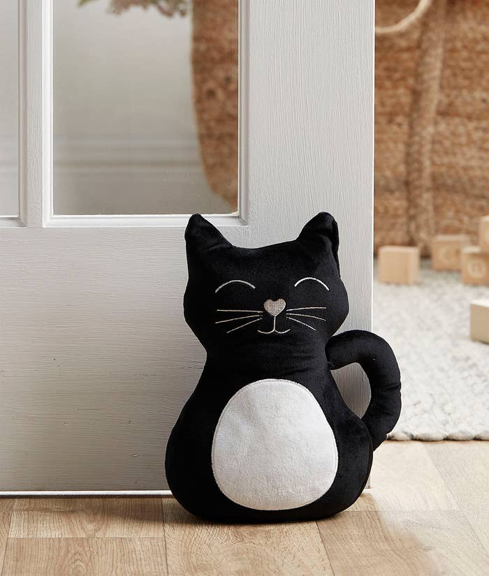 A cat-shaped door stopper holding a door open 