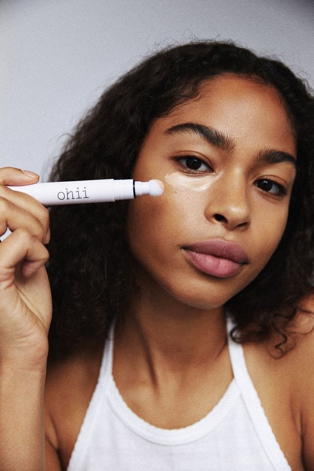 model applies the Wake Up Pen to under-eye skin