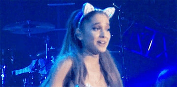 Ariana Grande shrugging on stage with cat ears