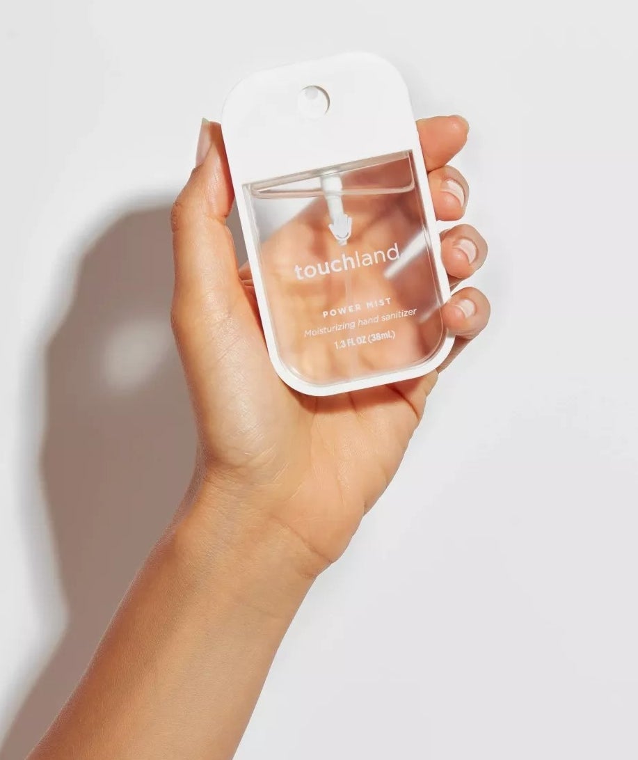 A model holding the clear, square bottle of sanitizer