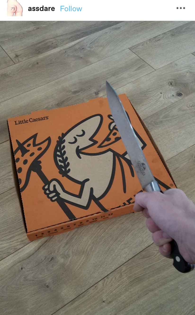 Someone holding a large knife over a Little Caesar&#x27;s pizza box