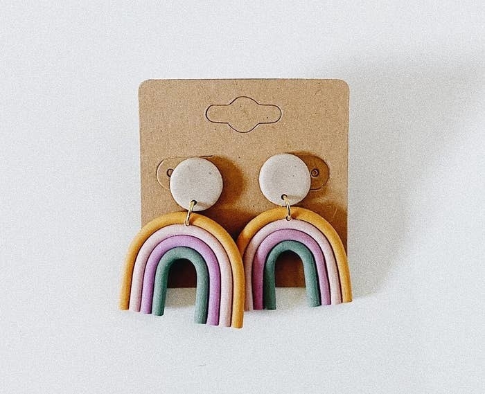 A pair of dangly clay earrings shaped like a rainbow 