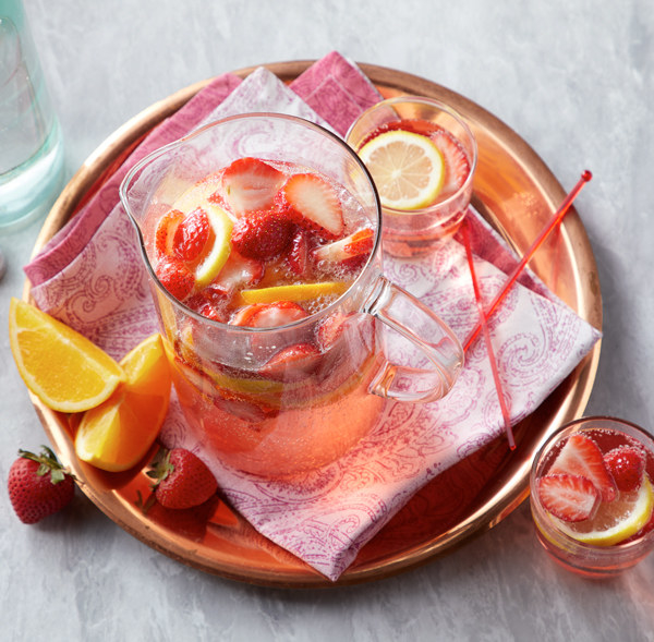 Large pitcher of Sparkling Strawberry Rose Sangria on a copper tray.