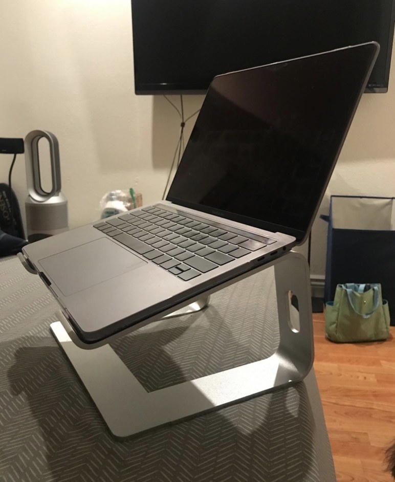 A laptop sitting in a stand on top of a desk