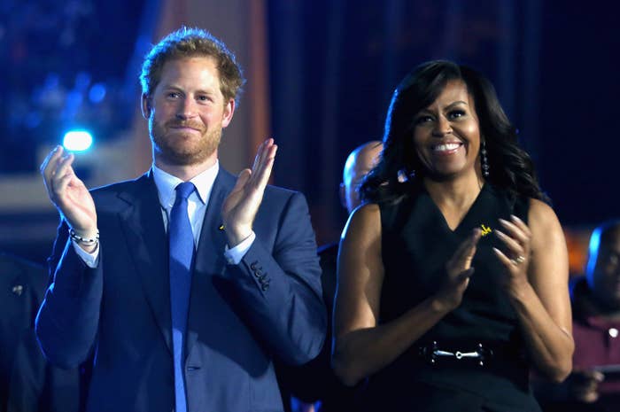 Michelle stands and claps next to Harry at an event