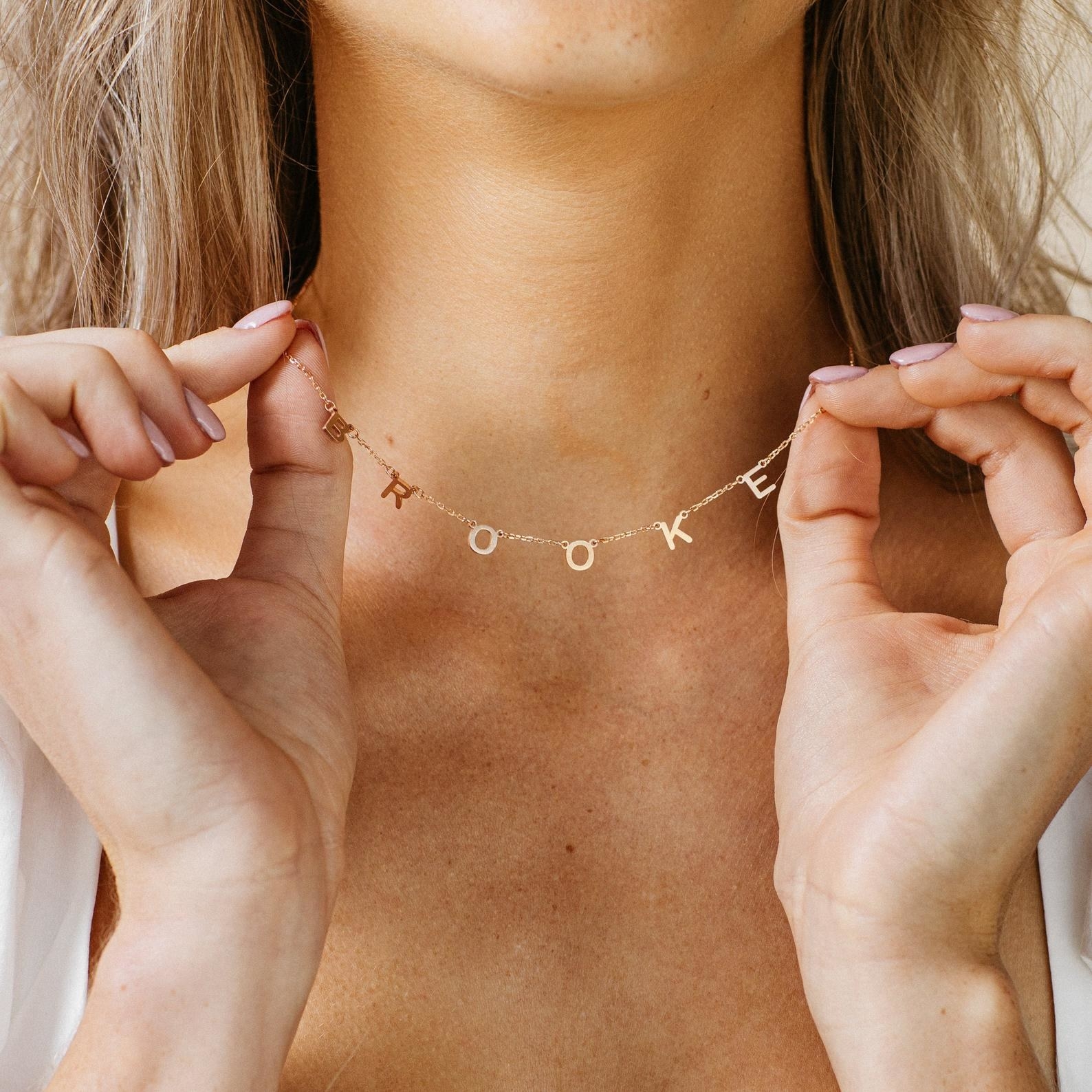 a model wearing a gold necklace that says &quot;brooke&quot;