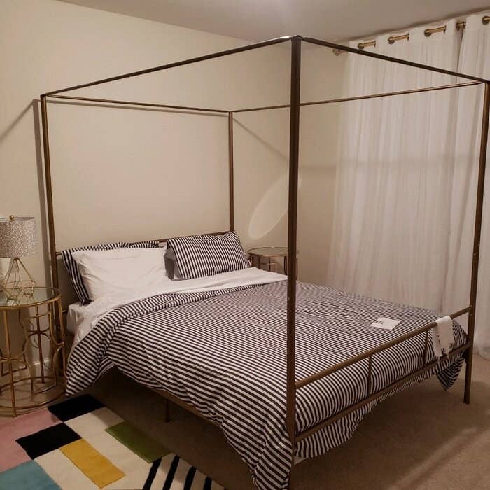 The bed, which has a rectangular metal canopy frame, which can hold up curtains or a fabric canopy, or be left bare