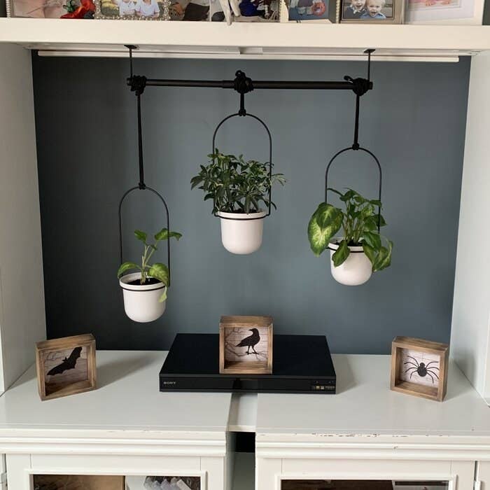 The planter, which has a straight metal rod with three adjustable strings dangling from it, which can be moved