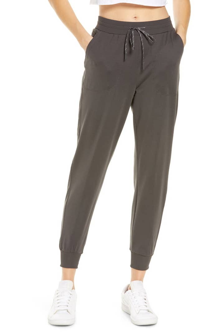 model wears gray joggers with white sneakers