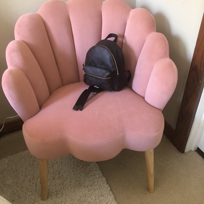 The chair, which has a scalloped seat and back, in light pink