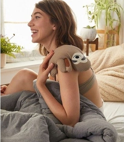 A person hugging the sloth-shaped heating pad 