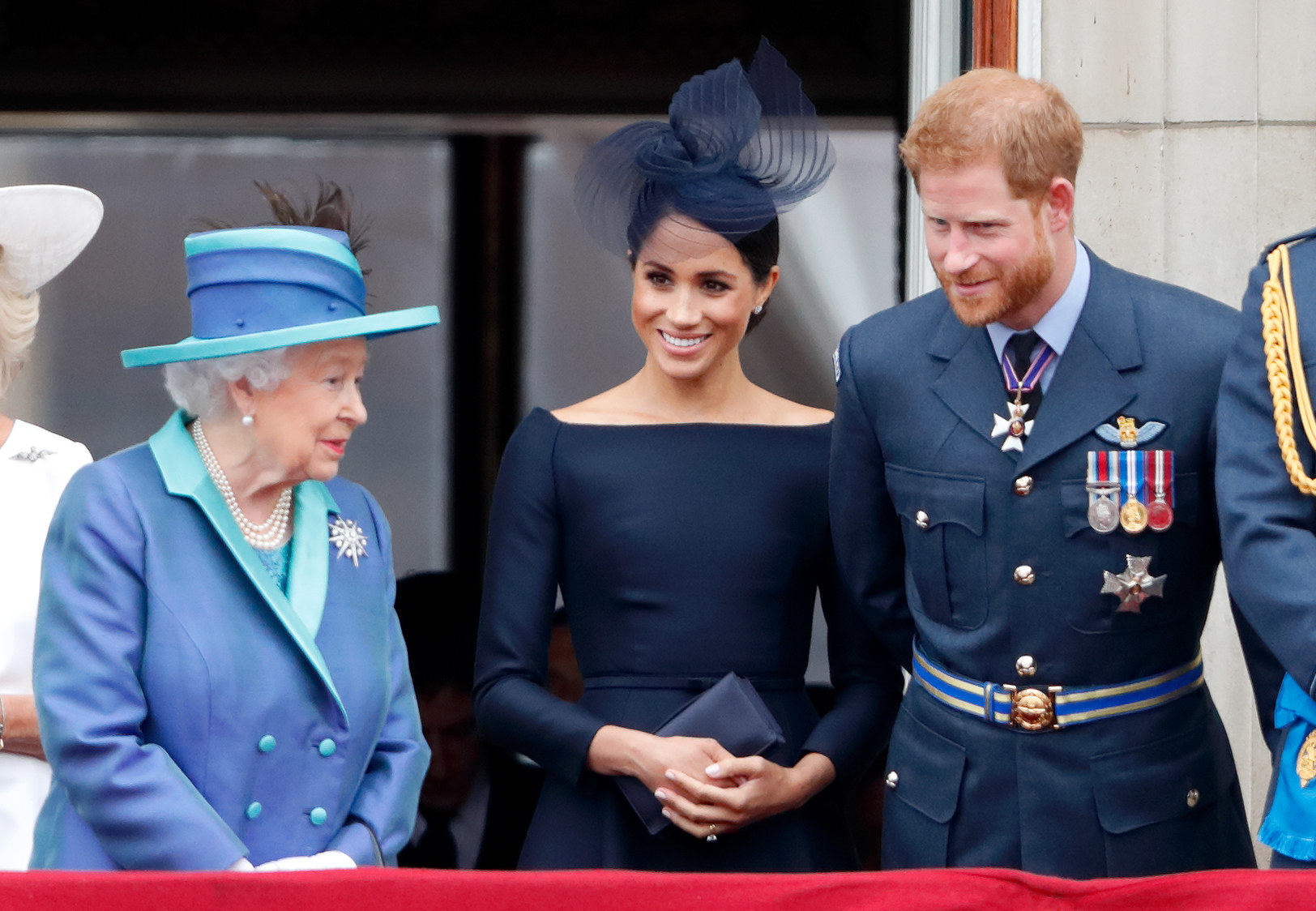 Harry and Meghan lean over to speak with the Queen at a formal event