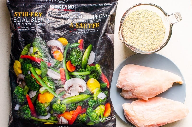 The ingredients necessary to make Instant Pot stir fry: frozen vegetables, chicken, and quinoa