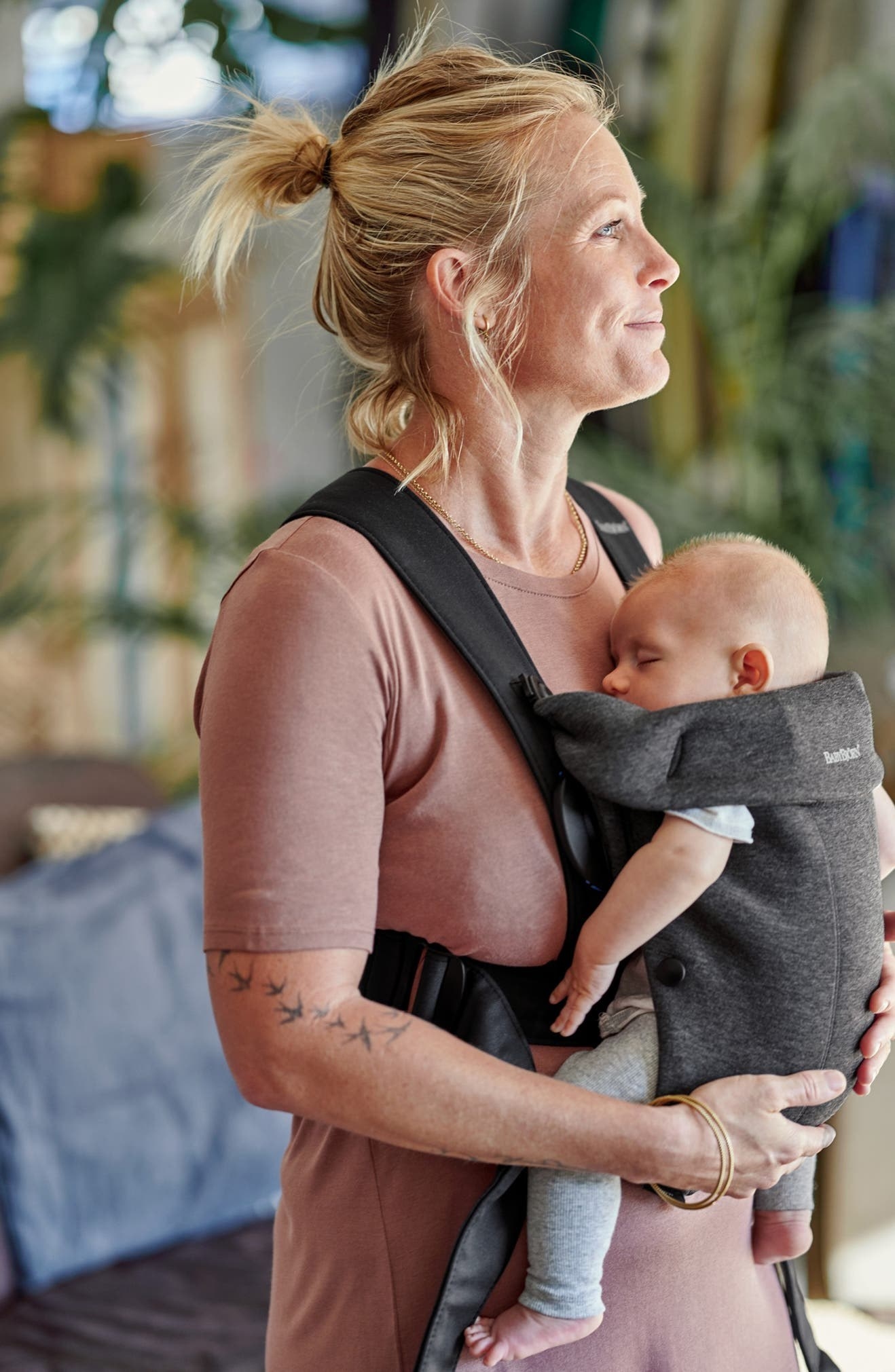Model uses the dark gray baby carrier to hold her baby