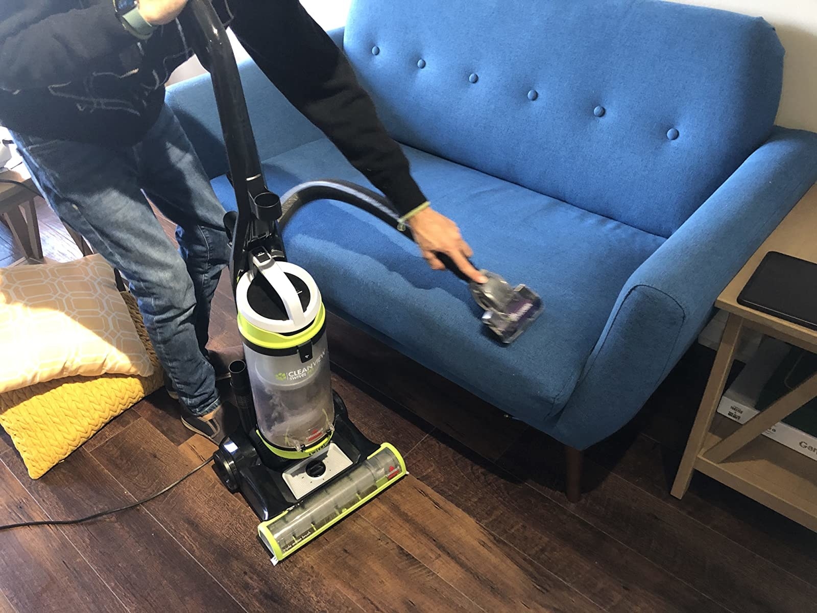 A person uses the vacuum on a couch