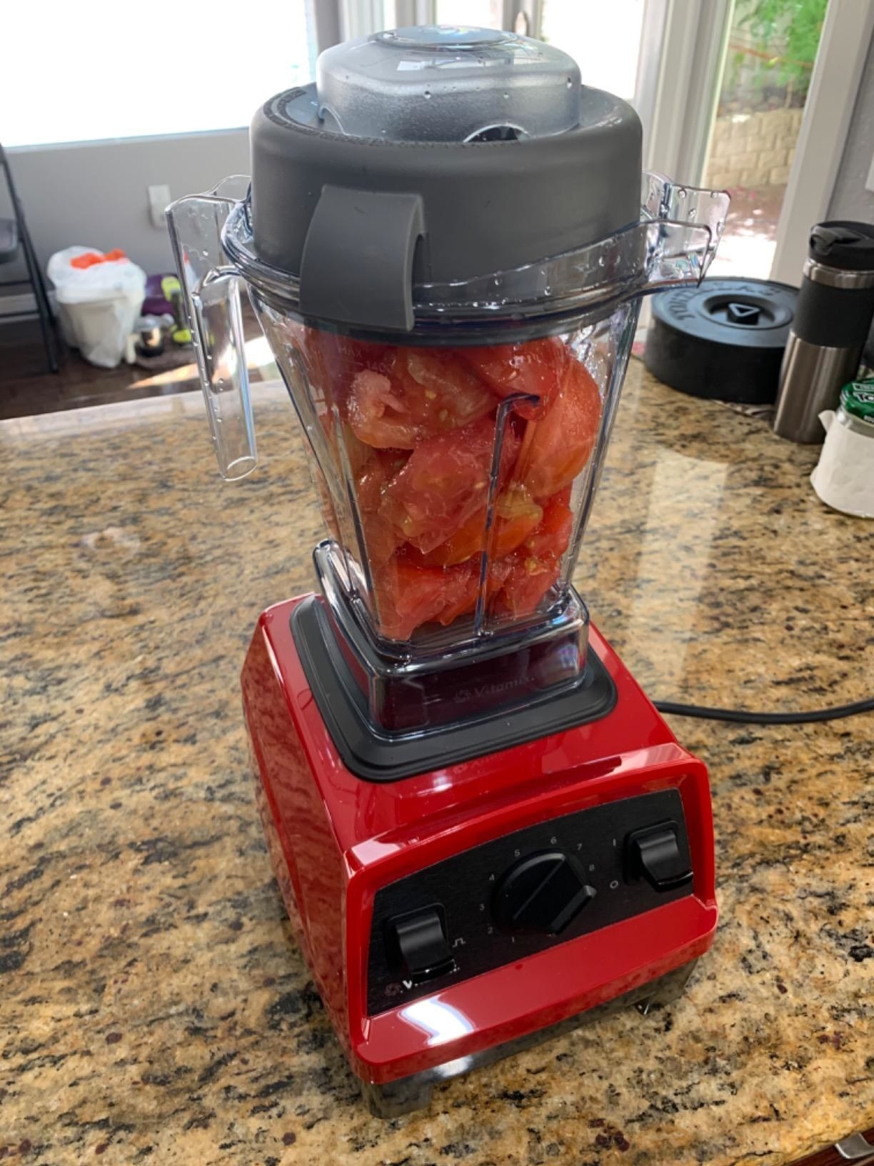 The blender in red filled with tomatoes