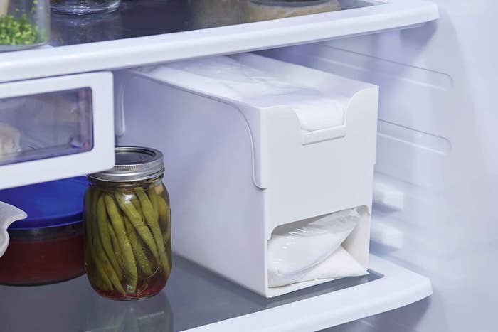 The milk bag dispensing organizer in a fridge beside a jar of green beans 