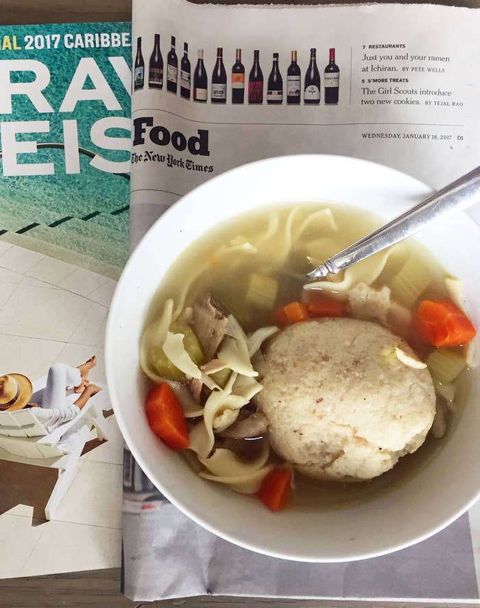 A bowl of matzo ball soup with egg noodles, vegetables, and chicken.