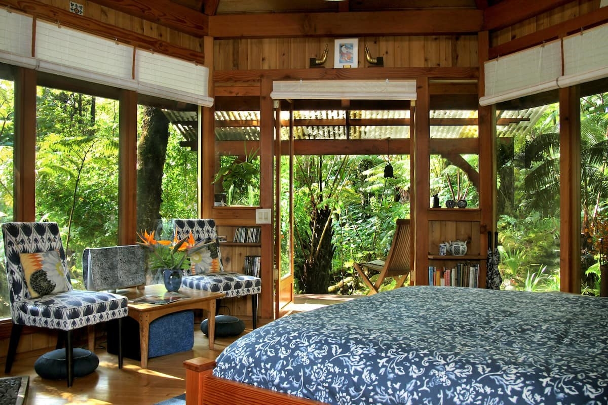 bedroom with glass walls looking out onto a rainforest