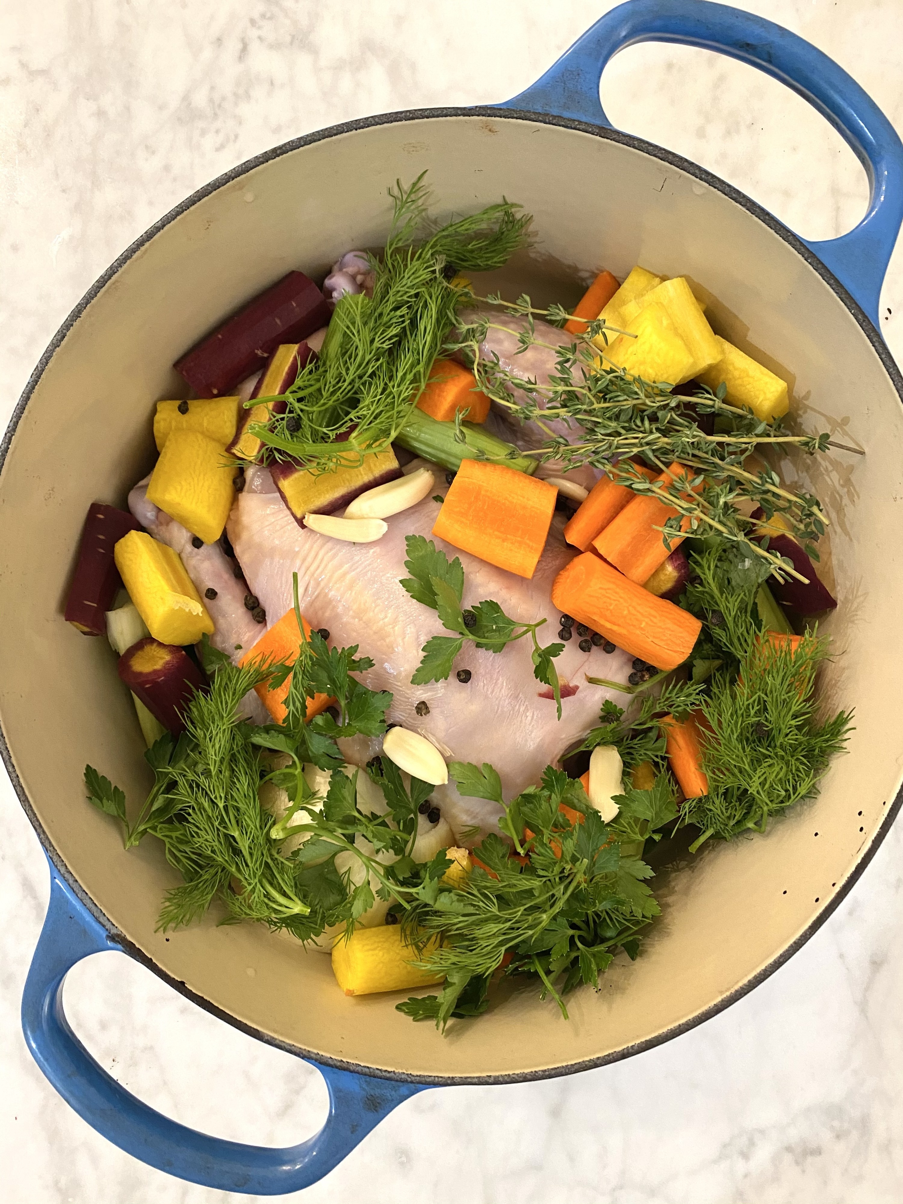 Ingredients for matzo ball soup in a Dutch oven.