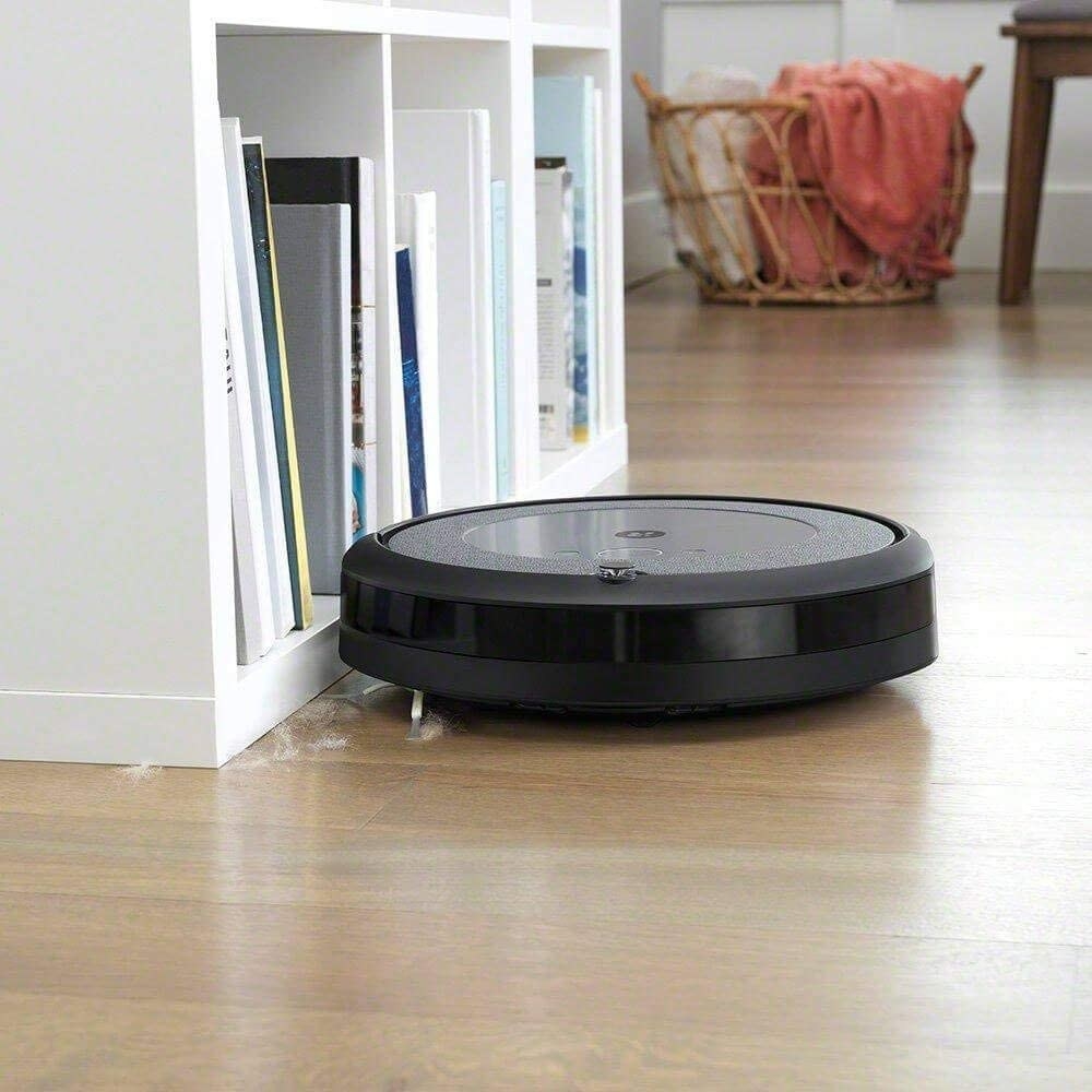 large circular robot vacuum vacuuming up dirt on a wood floor