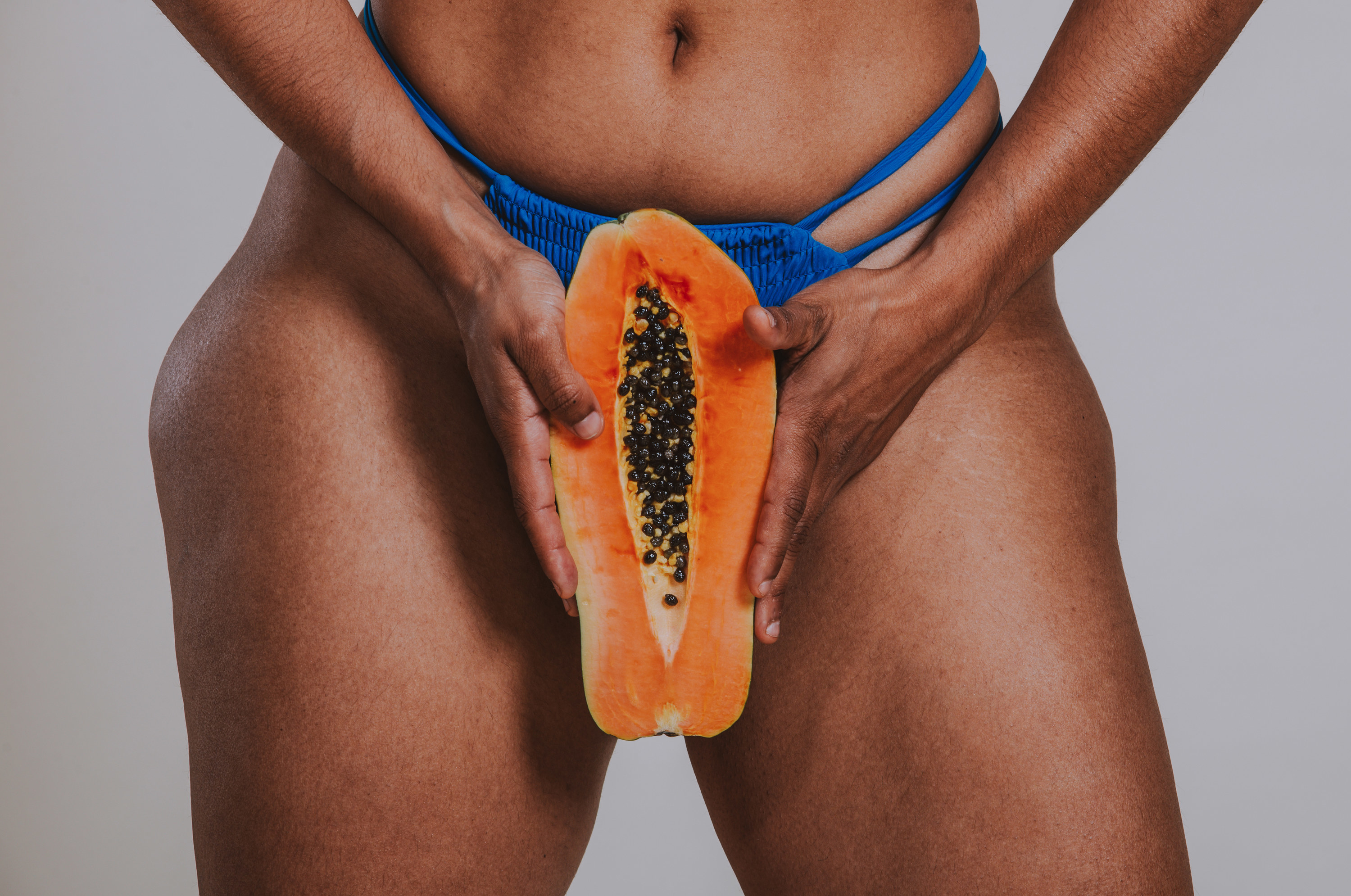An image of a woman holding a papaya in front of her pelvic region