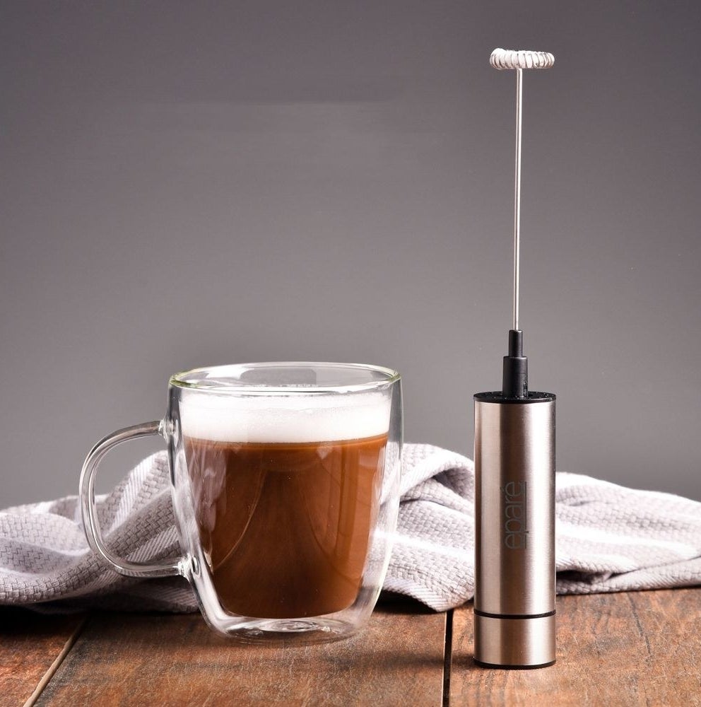 silver milk frother next  to a milk topped latte
