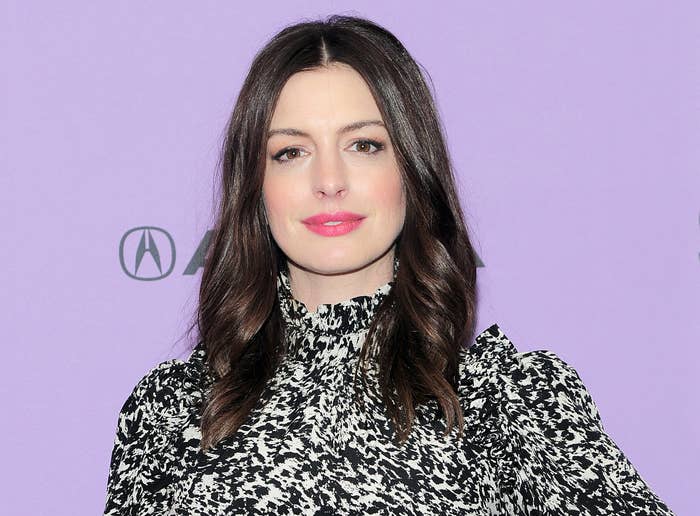 Anne softly smiles on a red carpet while wearing her hair down