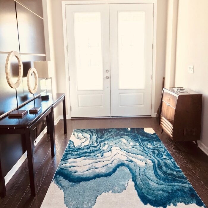 The rug, which has a blue and white wave/ inkstain-type print