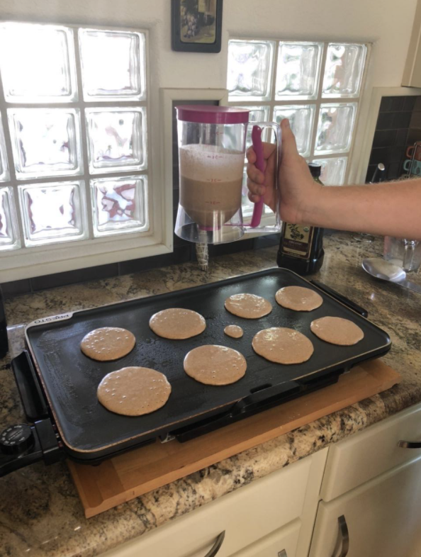 person using the batter dispenser to make pretty evenly sized pancakes on a griddle