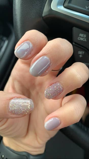 Reviewer with periwinkle nails and glittery white accent nail and thumb nail
