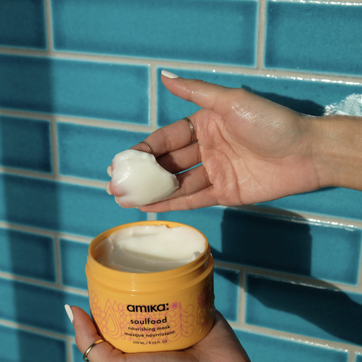 hand scoops up Amika Soulfood Nourishing Mask out of orange container